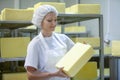 Female worker on yellow cheese production line in an industrial