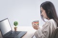 Female working with laptop computer while sitting at the office room in home, drinking coffee, social distancing alert, stay at
