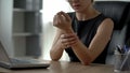 Female working on laptop, feeling wrist pain, osteoarthritis, joint inflammation Royalty Free Stock Photo