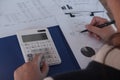 Female working in office, studying using calculator and writing something with documents and chart on table Royalty Free Stock Photo