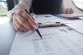 Female working in office, studying using calculator and writing something with documents and chart on table Royalty Free Stock Photo