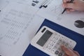 Female working in office, studying using calculator and writing something with documents and chart on table Royalty Free Stock Photo