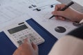 Female working in office, studying using calculator and writing something with documents and chart on table Royalty Free Stock Photo