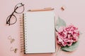 Female workspace with laptop, pink hydrangea, golden accessories, pink diary on pink background Royalty Free Stock Photo