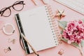 Female workspace with laptop, pink hydrangea, golden accessories, pink diary on pink background