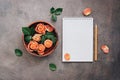 Female workspace with open notepad, ceramic bowl with flowers of coral roses and pencil. Top view, flat lay feminine background