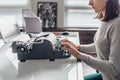 Female writer typing on a typewriter sitting in her workroom. Royalty Free Stock Photo