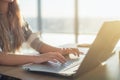 Female writer typing using laptop keyboard at her workplace in the morning. Woman writing blogs online, side view close