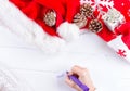 Female writing wish list in notebook near christmas gifts Royalty Free Stock Photo