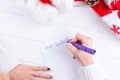 Female writing wish list in notebook near christmas gifts Royalty Free Stock Photo