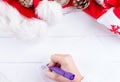 Female writing wish list in notebook near christmas gifts Royalty Free Stock Photo