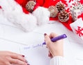 Female writing wish list in notebook near christmas gifts Royalty Free Stock Photo