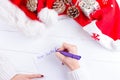 Female writing wish list in notebook near christmas gifts Royalty Free Stock Photo