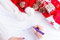 Female writing wish list in notebook near christmas gifts Royalty Free Stock Photo