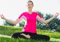 Female 26-32 years old in pink T-shirt is sitting and doing meditation