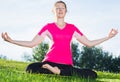 Female 26-32 years old in pink T-shirt is sitting and meditating