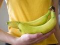 A female hand holding three bananas