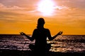 Female yoga lotos silhouette on beautiful beach during sunset. Royalty Free Stock Photo