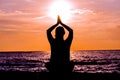Female yoga lotos silhouette on beautiful beach during sunset. Royalty Free Stock Photo