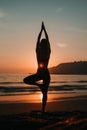 Female yoga practitioner in tree pose at beach during serene and picturesque sunset