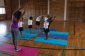 Female yoga teacher teaching yoga to school kids in school