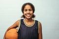 Young basketball player standing against wall. Confident teenage girl is holding ball. She is wearing black jersey Royalty Free Stock Photo