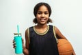 Young basketball player standing against wall. Confident teenage girl is holding ball. She is wearing black jersey Royalty Free Stock Photo