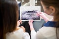 Female young dentist examining x-ray image with female patient in dental clinic and preparing for treatment. Dentistry