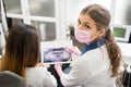 Female young dentist examining x-ray image with female patient in dental office, looking to the camera. Dentistry Royalty Free Stock Photo