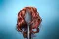 Females hair. Black hairbrush with a red wig, looks like a woman's head with a hairstyle. Blue background. Copy space. Royalty Free Stock Photo