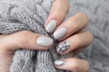 Females hand with modern manicure holds gray knitted sweater close up