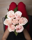 Females hands holding bouquet of beautiful pink roses. Top view