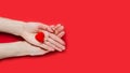 Females hands holds red heart on red background. Close-up. Top view