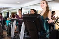 Females training on elliptical trainers in fitness club