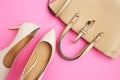 Feminine accessories flat lay. Woman shoes and bag on pink background. Beige color woman accessories. Text space. Top view.