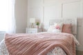 Feminine bedroom with floral bedsheet and pink blanket on the bed against wall Royalty Free Stock Photo