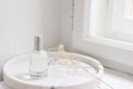 Feminine cosmetic still life scene. Glass bottle, flacon with perfume or eau de toilette and dry grass on white marble