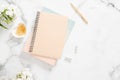 Feminine desk with blank paper notepad, white flowers and golden stationery on marble background. Fashion blogger home office