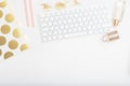 Feminine desk with pink and gold objects on a white background.