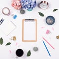 Feminine desk workspace frame with beauty arrangement of bouquet hydrangeas, clipboard, notebook, clips, clock, pencil and candle