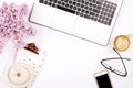 Top view of female worker desktop with laptop, flowers and different office supplies items. Feminine creative design workspace.