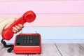 A feminine elegant beautifully manicured woman`s hand holding an old red telephone handset over abstract striped background Royalty Free Stock Photo