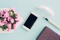 Feminine flat lay on blue background, top view of woman`s desktop with envelope, flowers, pen, notepad and smartpho Royalty Free Stock Photo