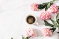 Feminine floral composition. Cup of coffee and pink peonies flowers on white marble table background. Empty space. Flat