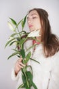 Feminine girl in a white fur coat with a branch of lilies in the background in the Studio Royalty Free Stock Photo