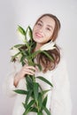 Feminine girl in a white fur coat with a branch of lilies in the background in the Studio Royalty Free Stock Photo