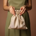 Feminine hand clutches canvas bag, symbolizing support on beige backdrop