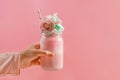 Feminine hand holding a glass jar with a milkshake topped with cotton candy