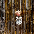 Feminine hand holds clock showing almost midnight