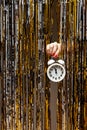 Feminine hand holds clock showing almost midnight